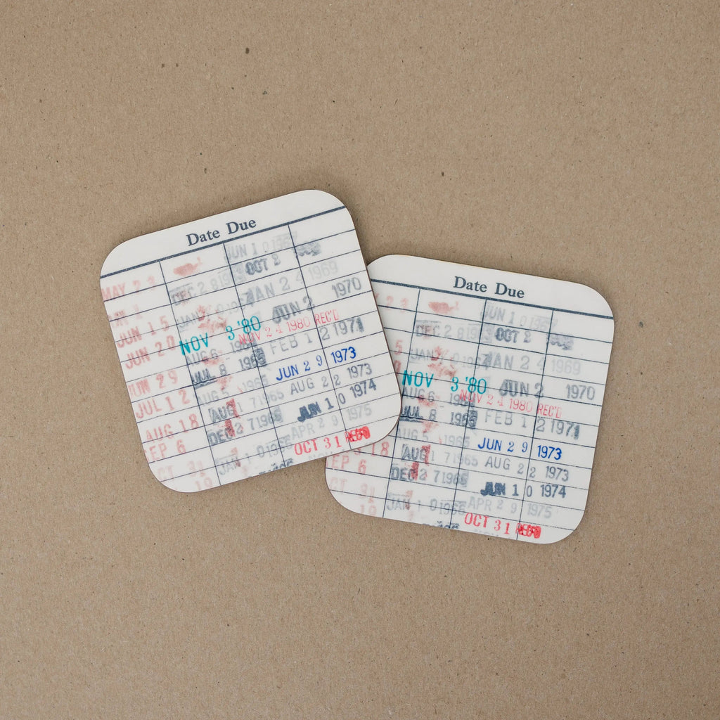 Two library due-date coasters on kraft paper, with Date Due grid and stamped dates.