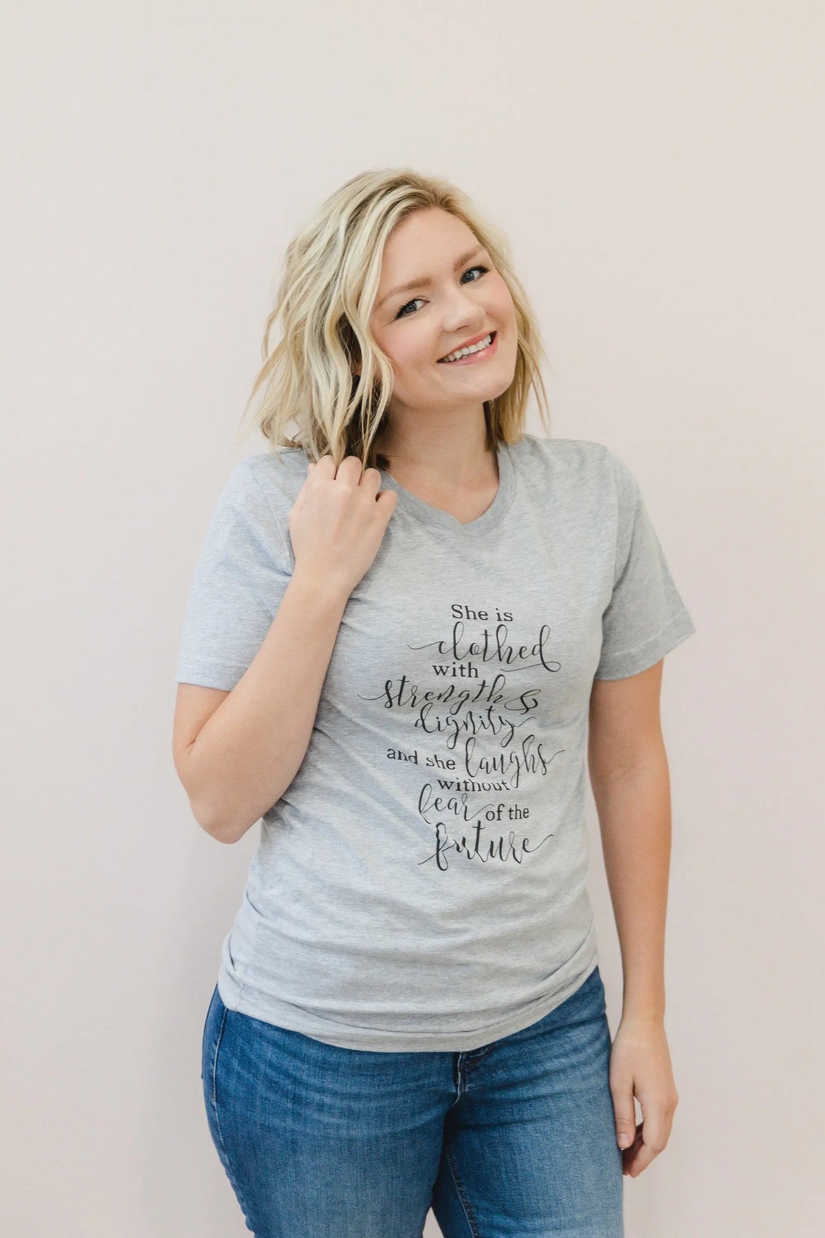 Heather gray women's graphic T-shirt with "She is clothed..." verse on front.