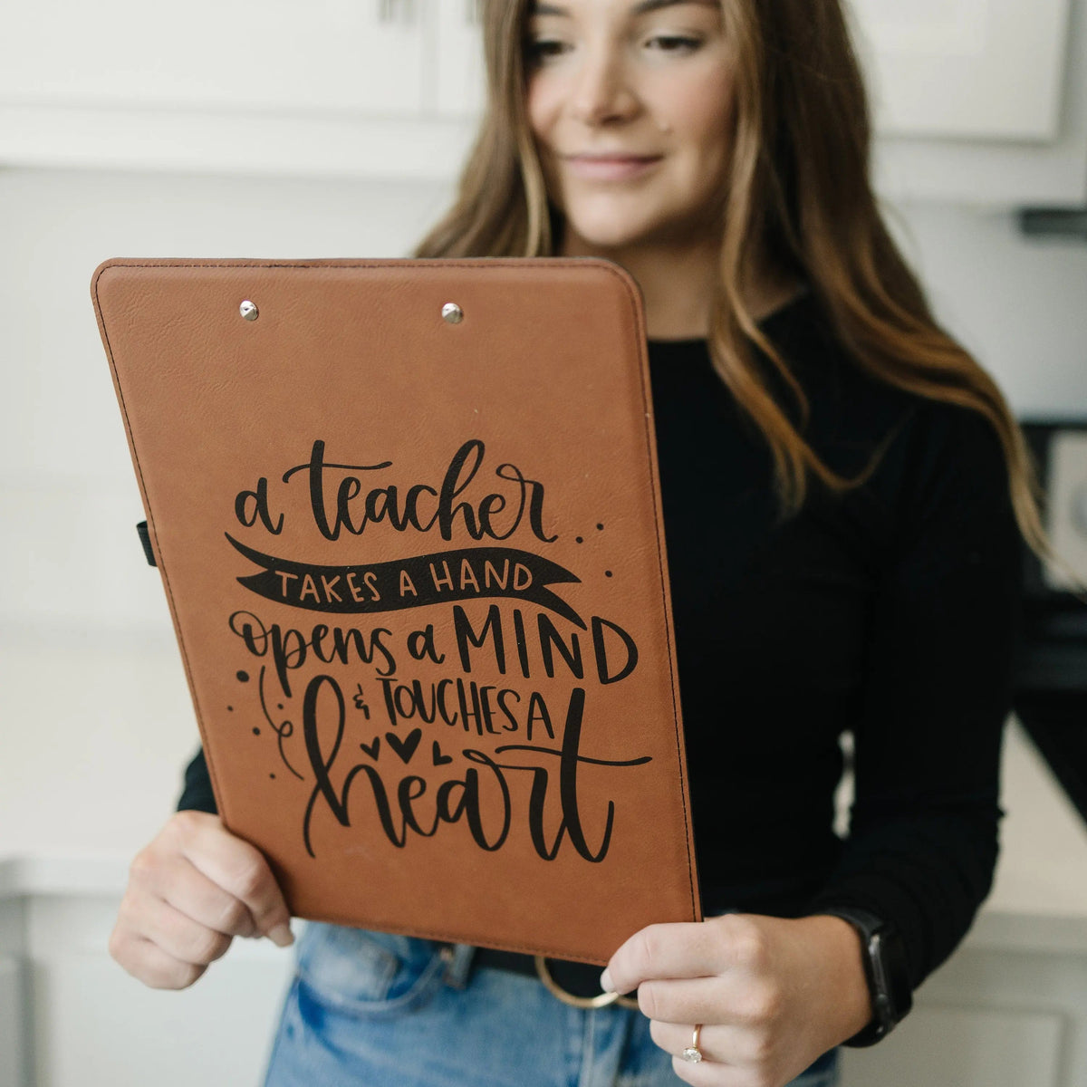 Brown leather clipboard with teacher quote design, held by a person