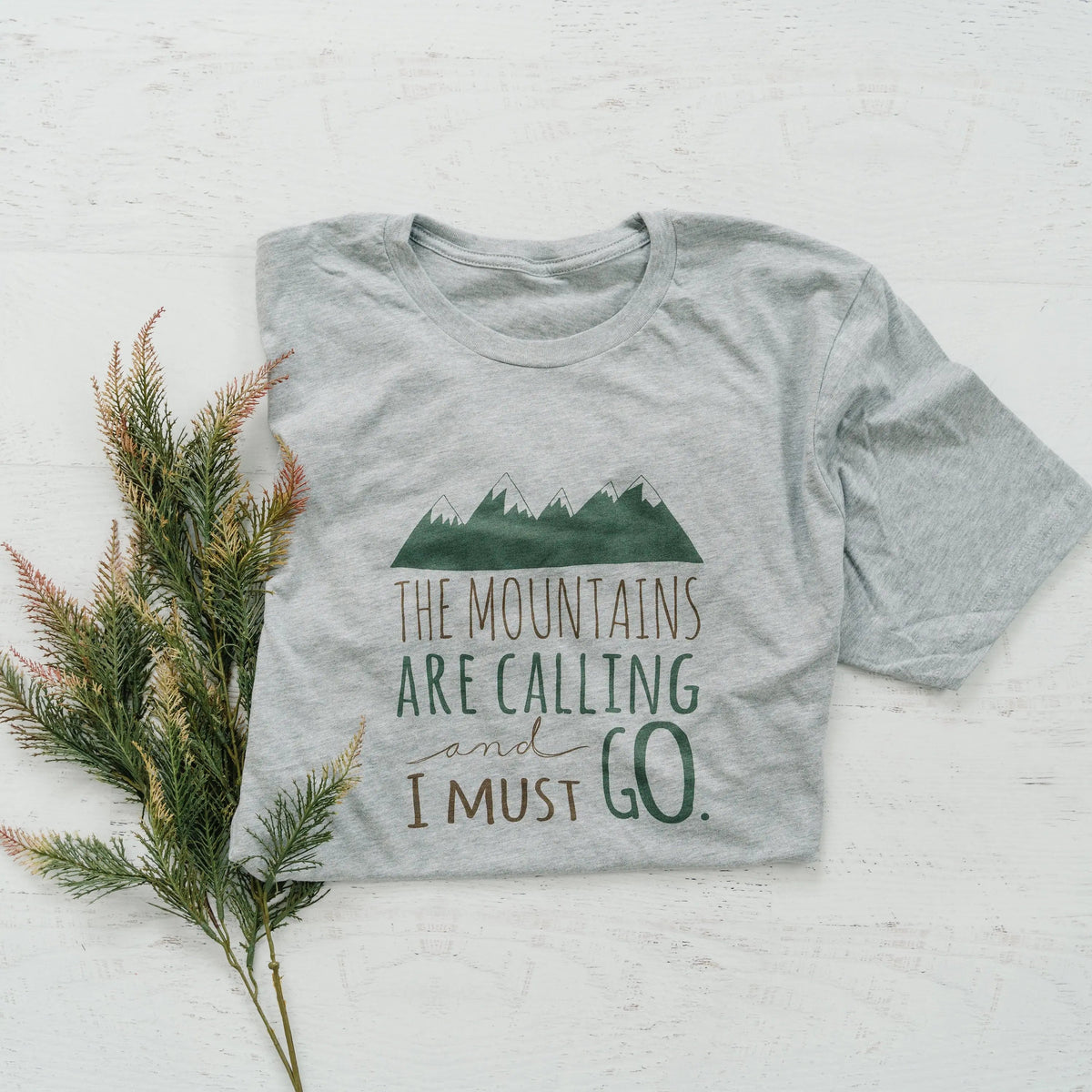 Gray crewneck unisex t-shirt with green mountains and "The Mountains are Calling" print
