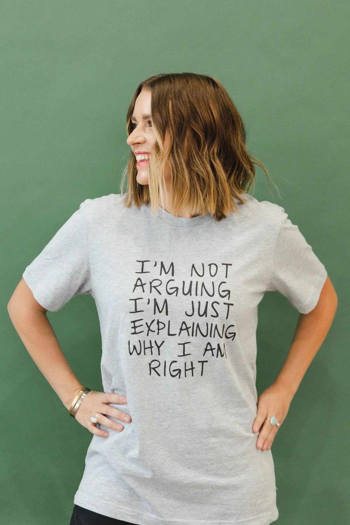 Model wearing heather gray unisex T-shirt with back quote: “I’m not arguing, I’m just explaining…”