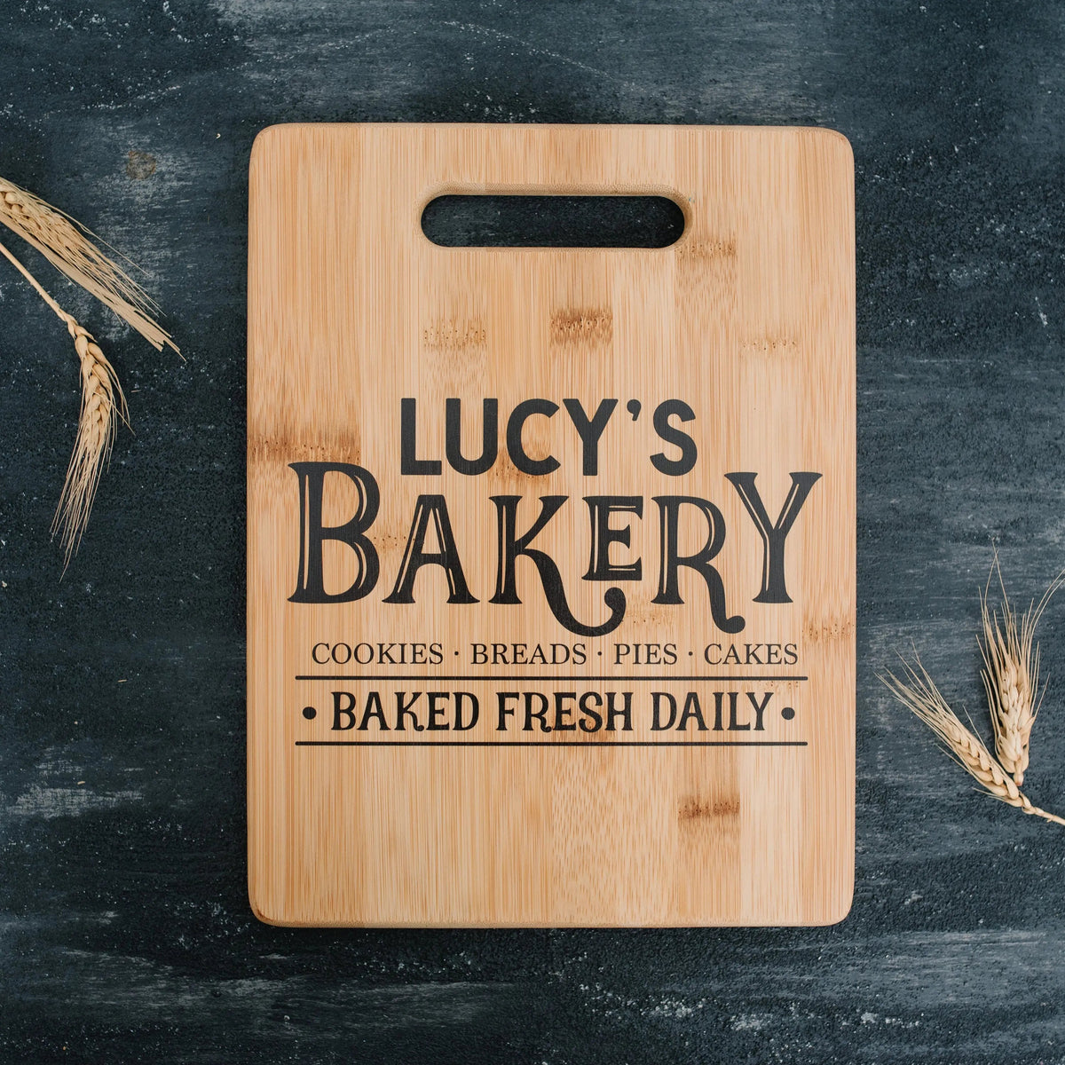 Light wood cutting board with handle, 'LUCY'S BAKERY' lettering centered