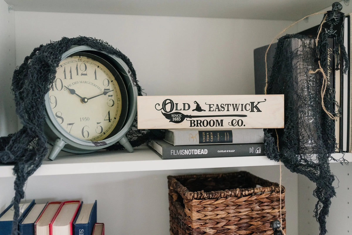 Cream wood shelf sign with Old Eastwick Broom Co. lettering