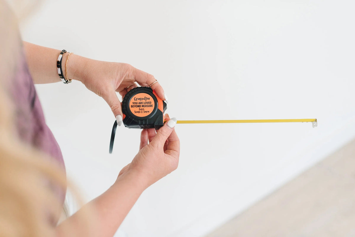 Personalized tape measure in hand with orange housing and extended yellow tape
