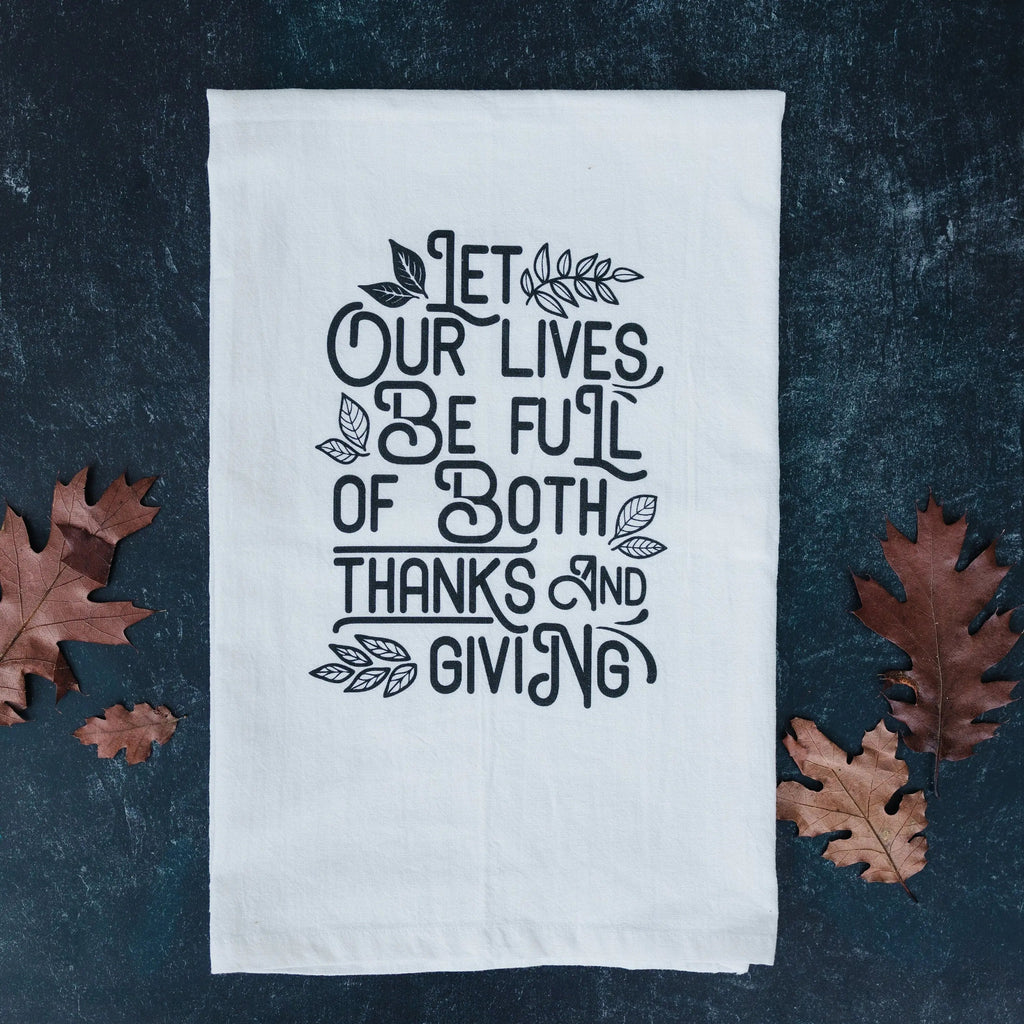White Thanksgiving kitchen towel with black “Let our lives be full…” lettering and leaf accents