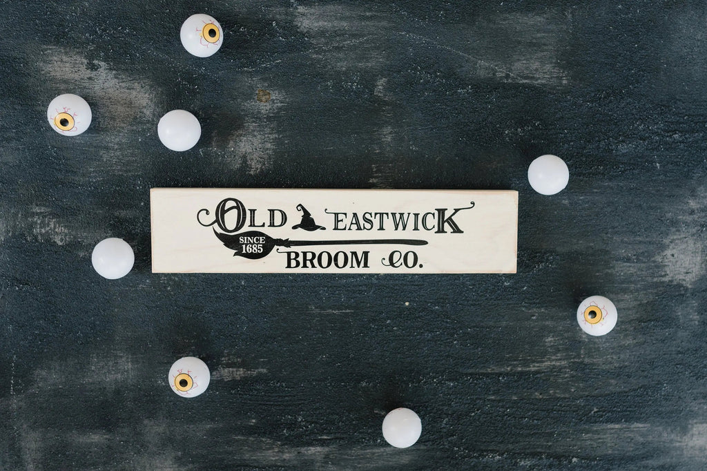 Cream framed wood sign reading Old Eastwick Broom Co., centered