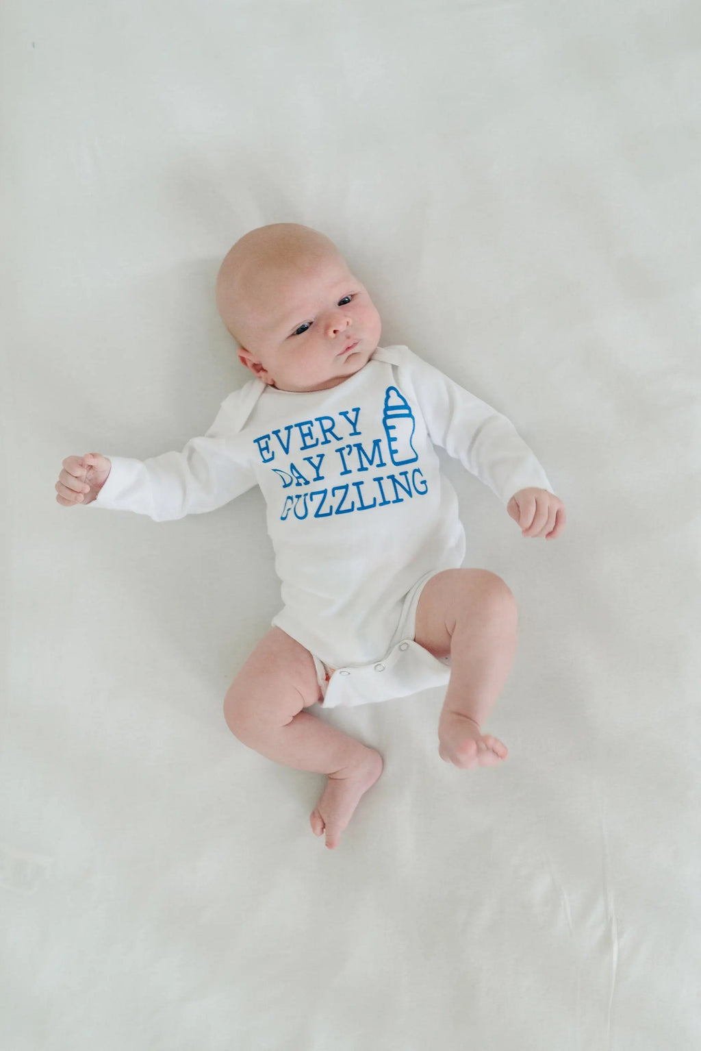White newborn bodysuit with blue “Every Day I’m Guzzling” slogan, baby wearing it