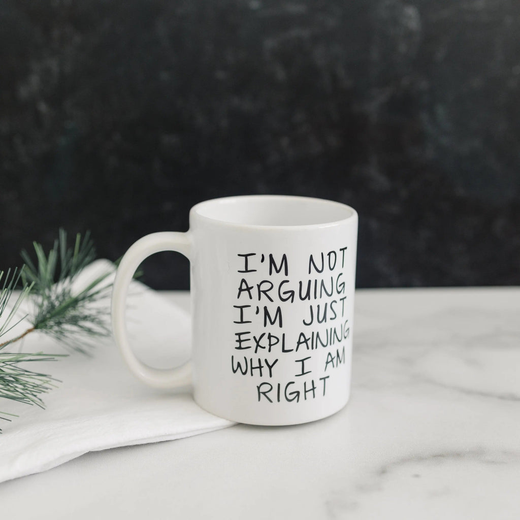 White ceramic coffee mug with humorous quote, placed on a white surface