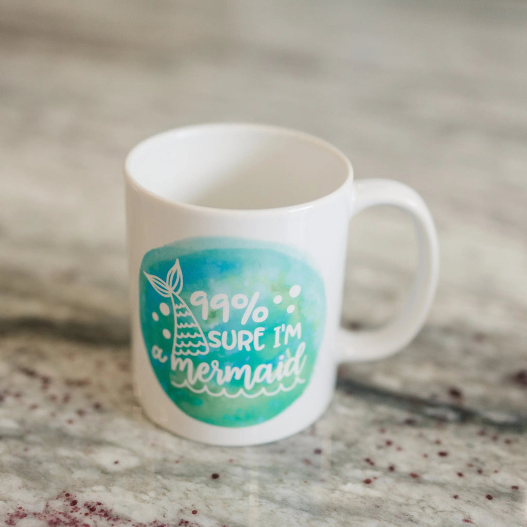 White ceramic mug with teal mermaid watercolor graphic and '99% sure I'm a mermaid' text