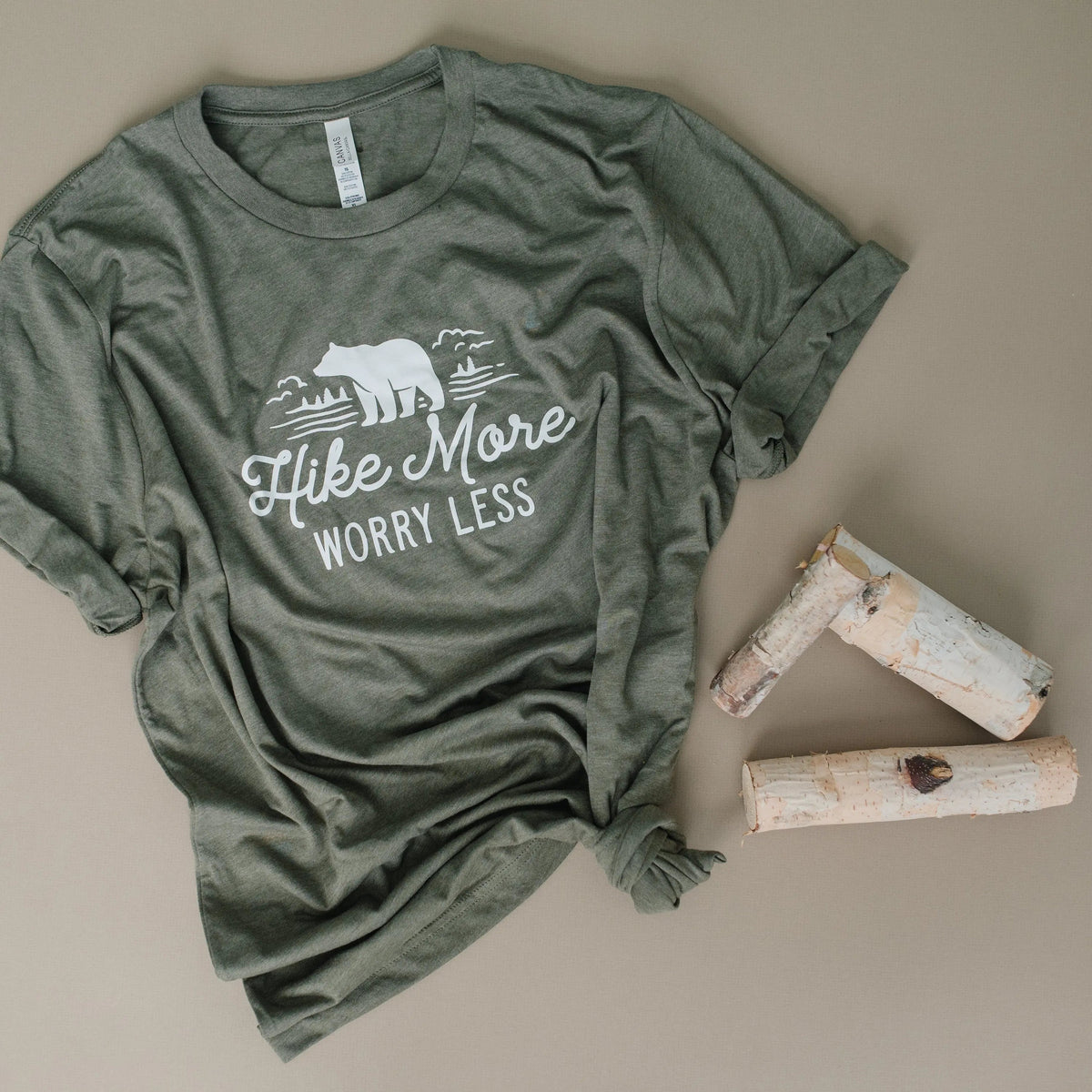 Olive green unisex t-shirt, bear “Hike More Worry Less” print, folded top view