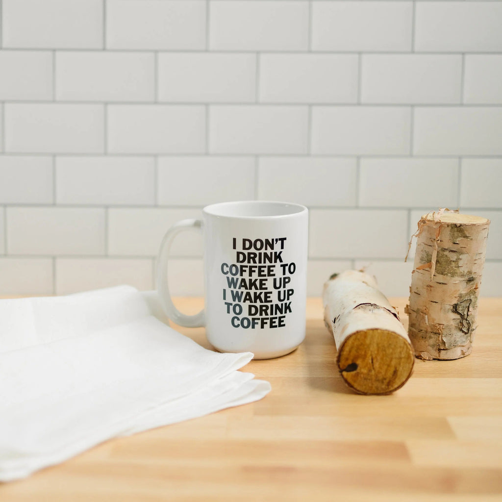 White coffee mug with "I don't drink coffee..." quote, near a birch log