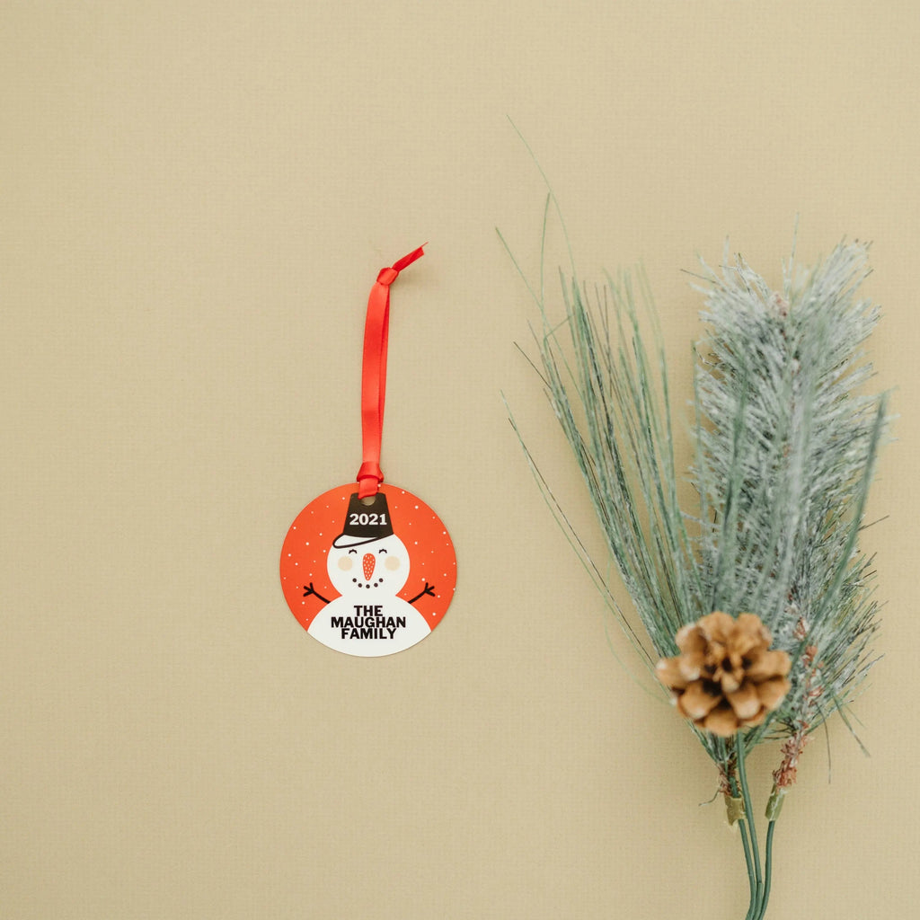 Hanging round snowman ornament with 2021 and “The Maughan Family” on a red circle