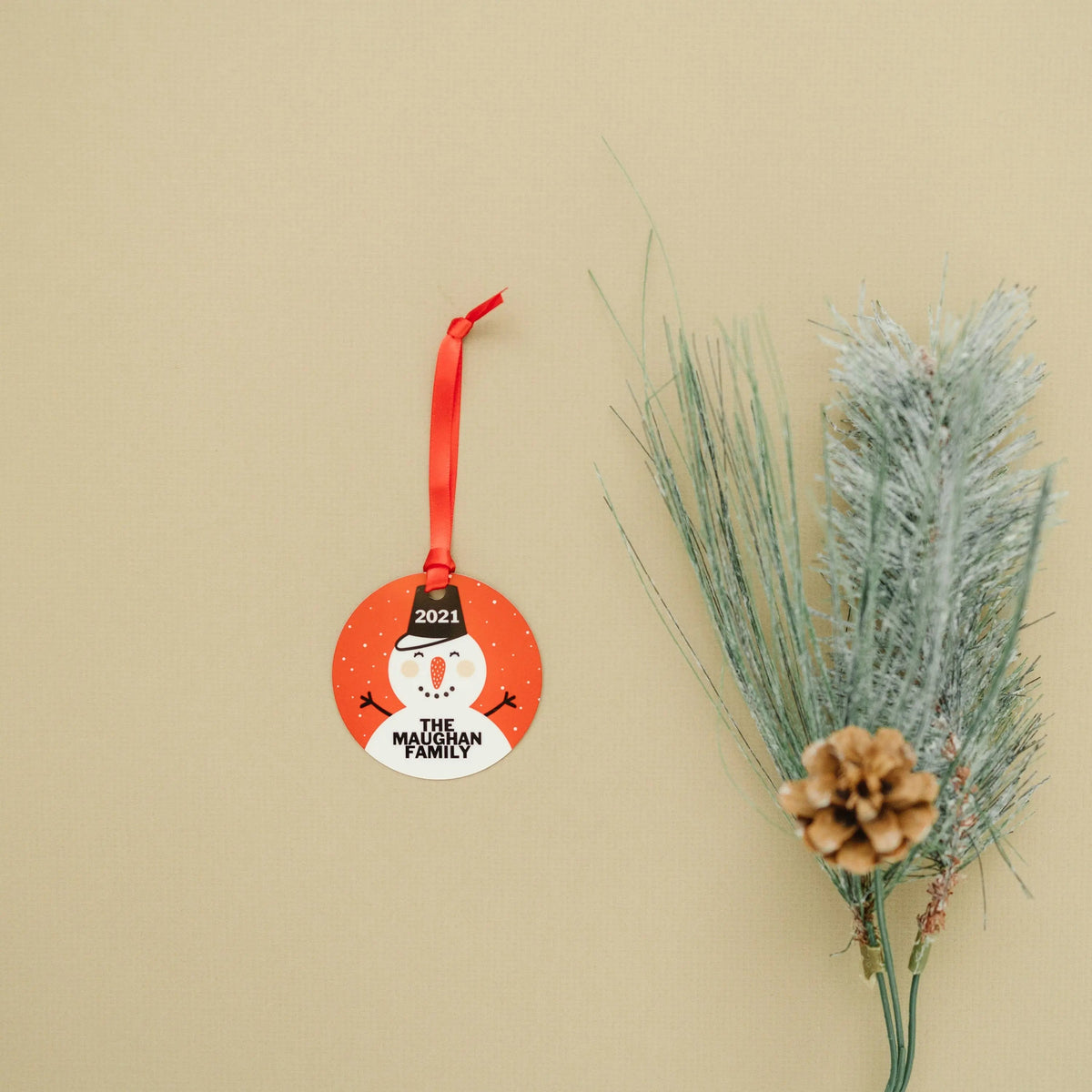 Hanging round snowman ornament with 2021 and “The Maughan Family” on a red circle