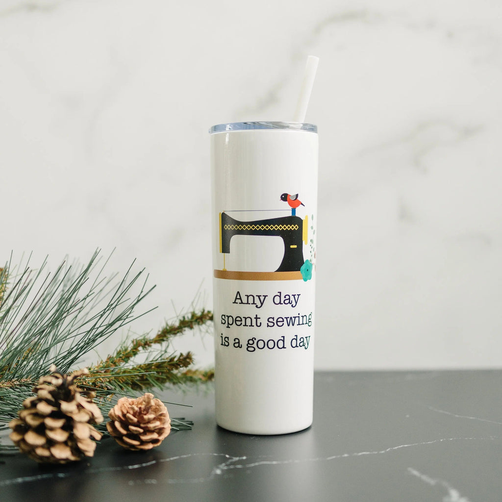 White skinny travel tumbler with straw, clear lid, and sewing machine quote graphic