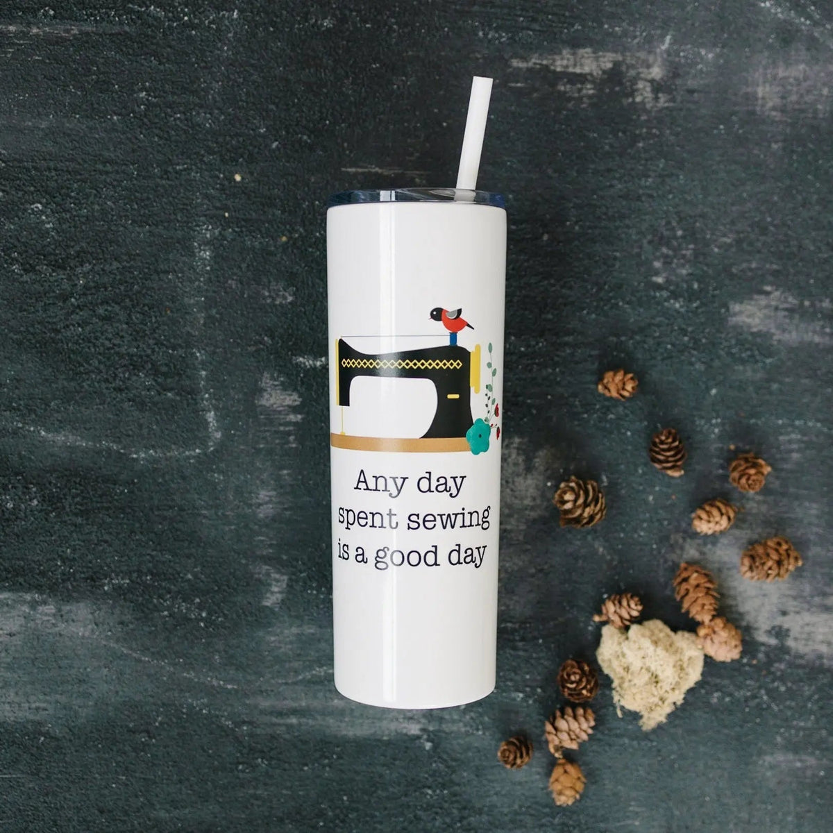 White skinny travel tumbler with straw and colorful sewing machine decal