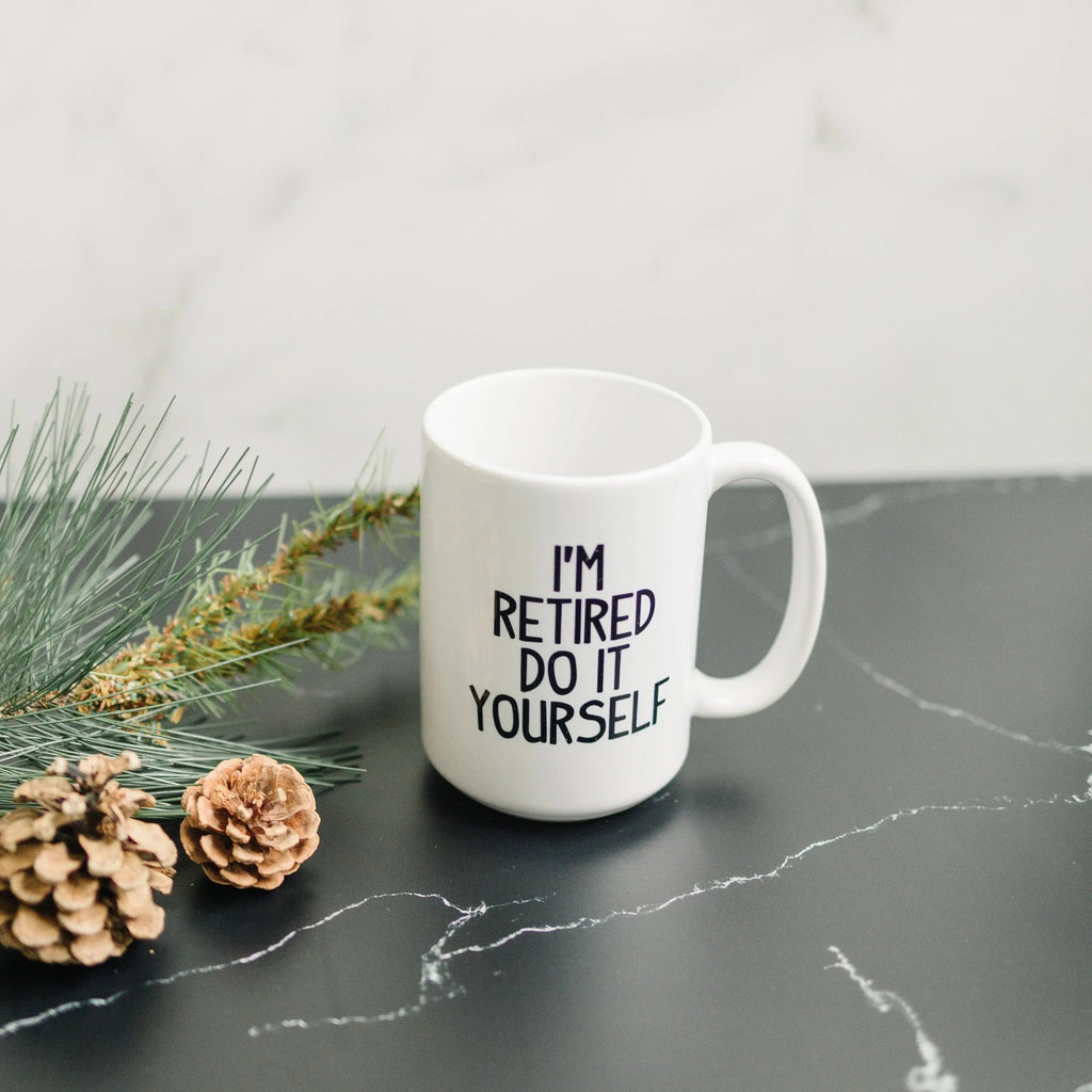 White ceramic coffee mug with "I'm retired do it yourself" print and curved handle