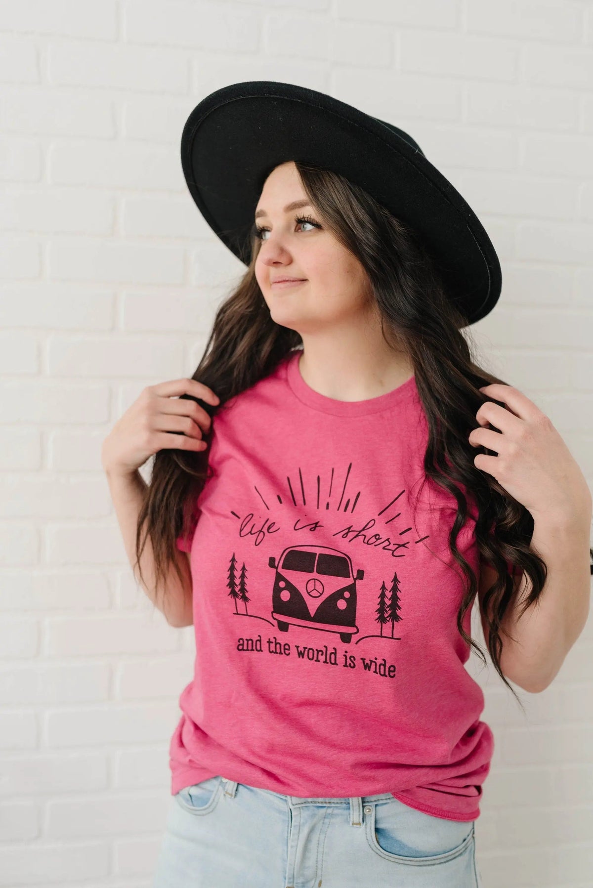 Women’s pink graphic t-shirt with camper van and “Life is short” slogan, on model