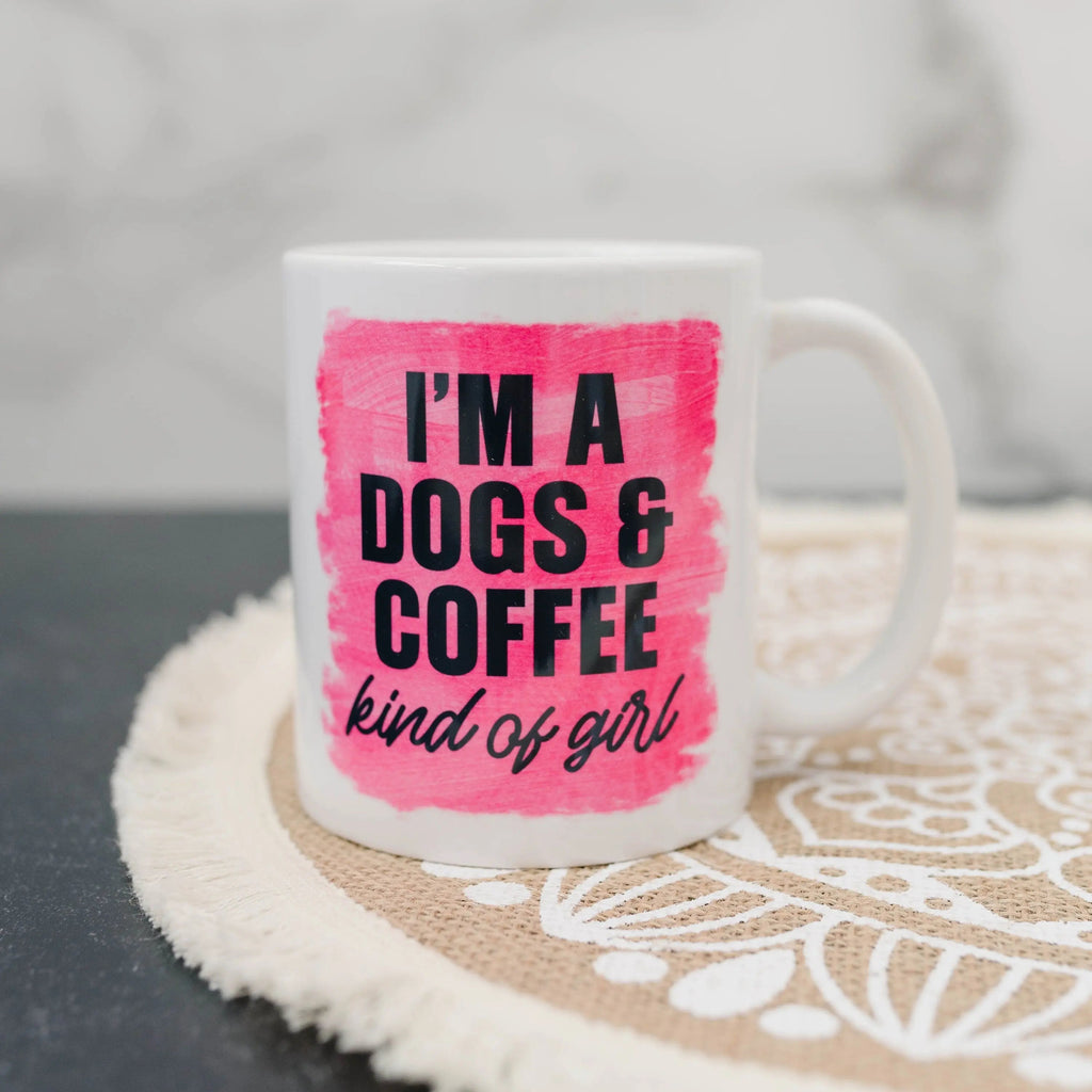 White coffee mug with pink brushstroke text: “I'm a DOGS & COFFEE kind of girl”