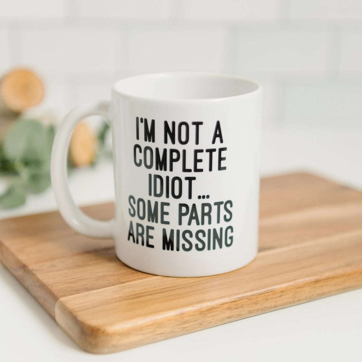 White ceramic coffee mug with quote: "I'M NOT A COMPLETE IDIOT... SOME PARTS ARE MISSING"