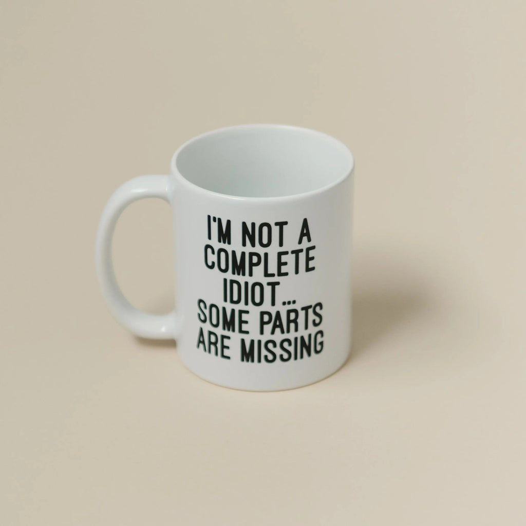 White ceramic coffee mug with text: "I'M NOT A COMPLETE IDIOT... SOME PARTS ARE MISSING"