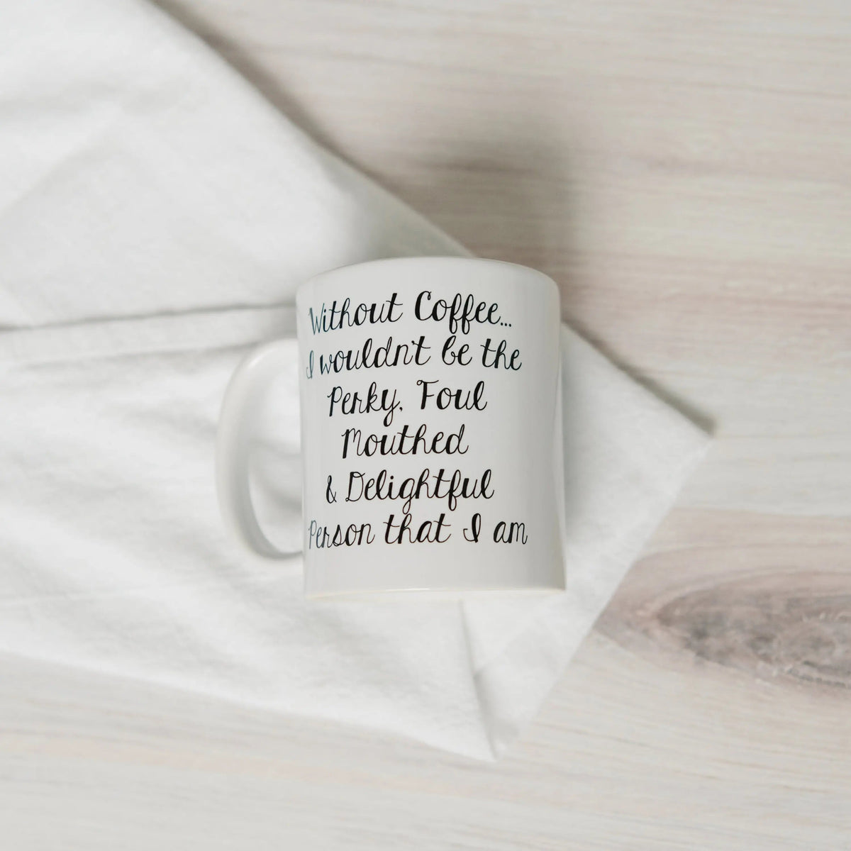 White ceramic coffee mug with black cursive quote on the front