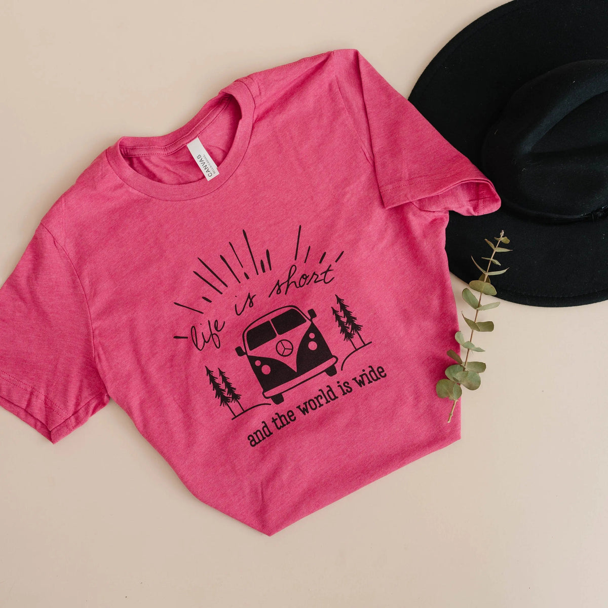 Pink graphic t-shirt with camper van and trees design, folded flat