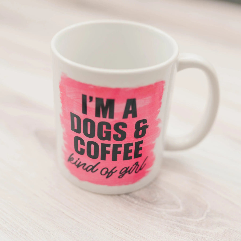 Close view of white coffee mug with pink text: “I'm a DOGS & COFFEE kind of girl”