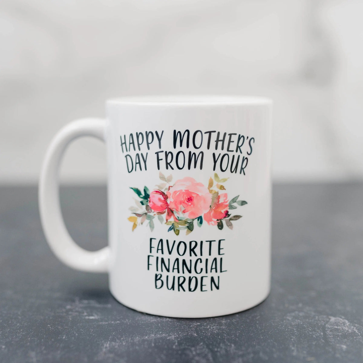 White ceramic coffee mug with floral “Happy Mother’s Day” and “Favorite Financial Burden” text