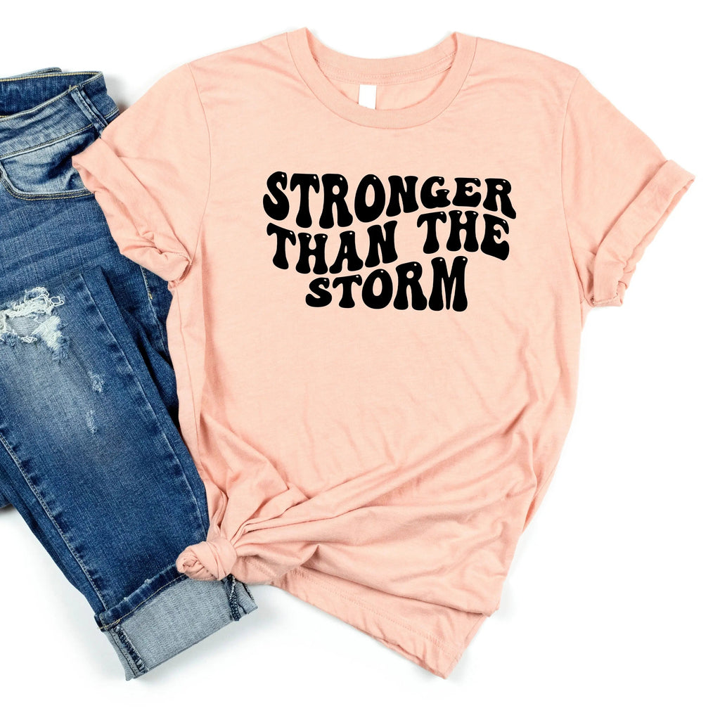 Peach unisex T-shirt with "STRONGER THAN THE STORM" graphic text on front