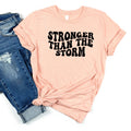 Peach unisex T-shirt with "STRONGER THAN THE STORM" graphic text on front