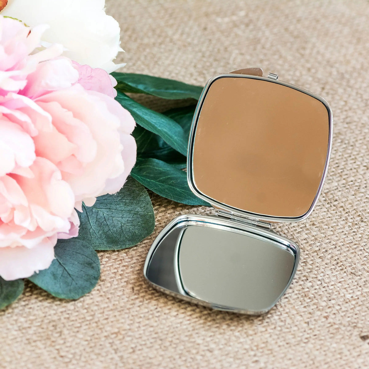 Silver compact mirror open, showing two square reflective panels