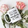 White ceramic coffee mug with black text: “It’s fine, I’m fine, everything is fine.”