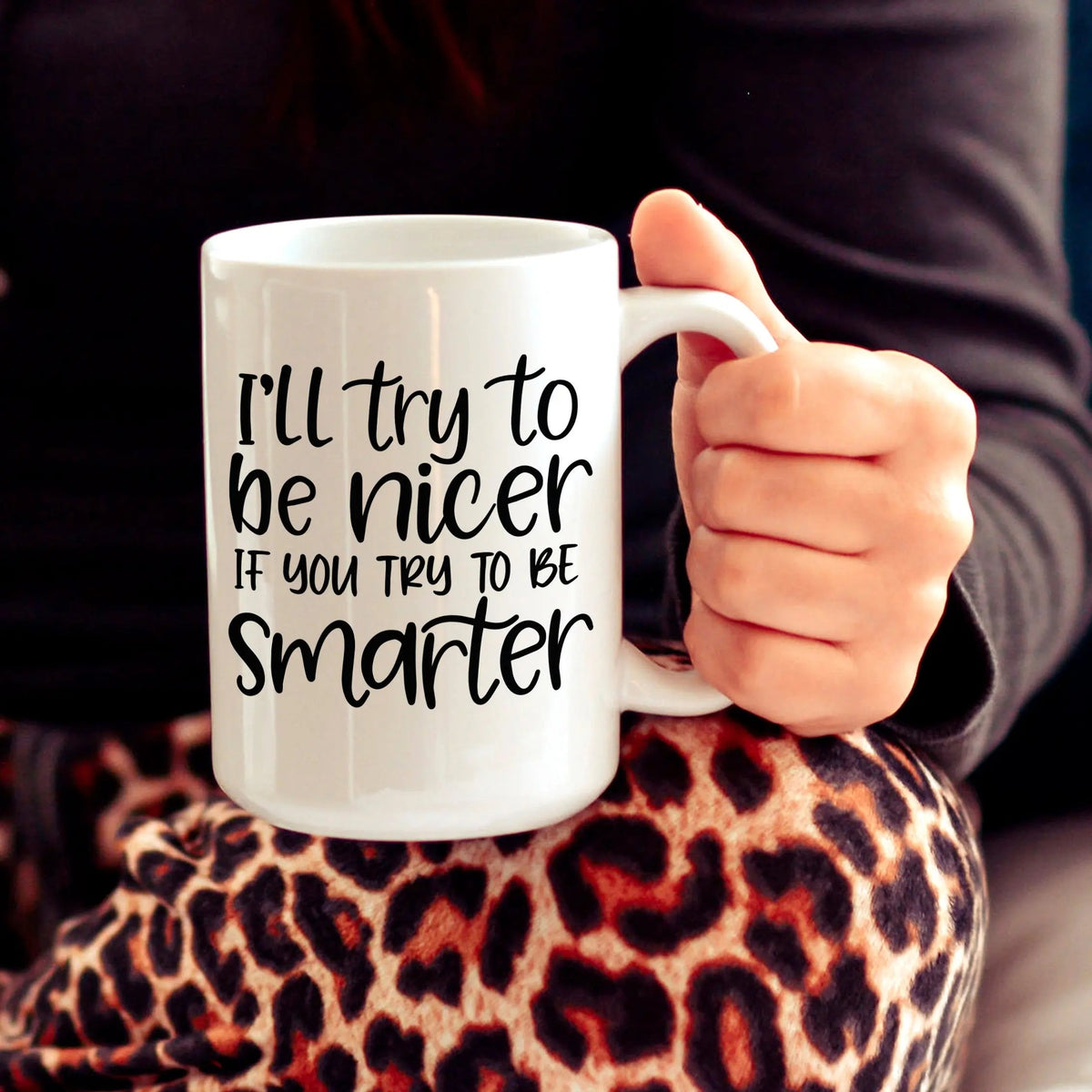 White ceramic coffee mug with black quote, held in a hand.