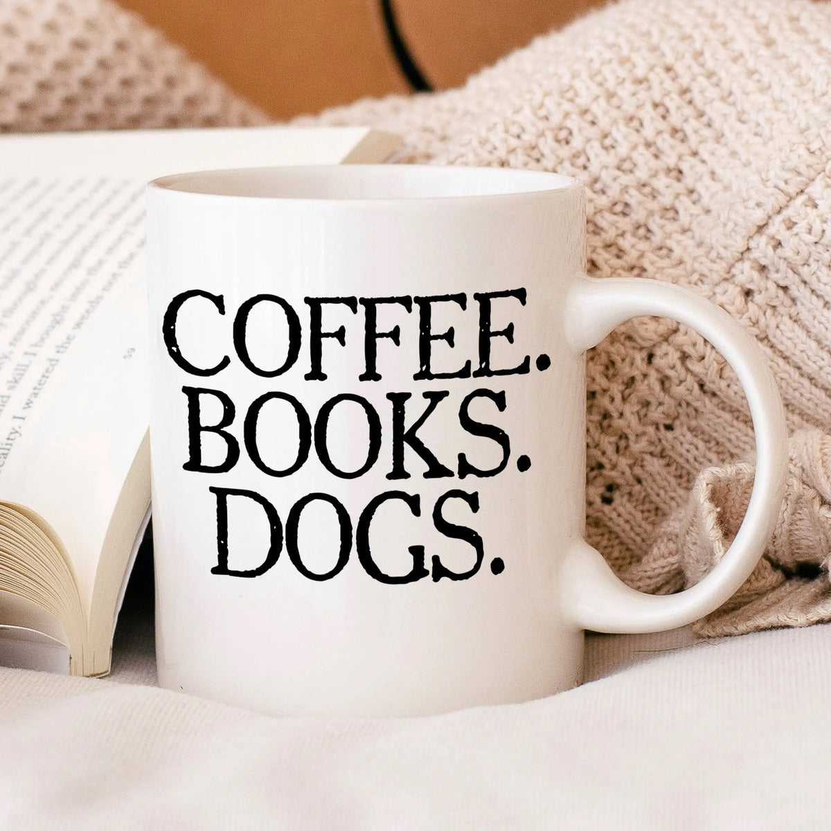 White ceramic coffee mug with 'COFFEE BOOKS DOGS' text and side handle