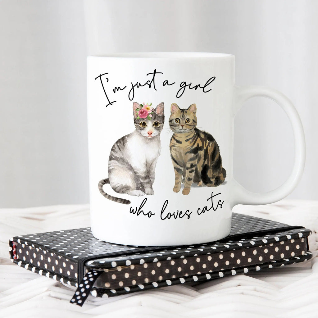 White ceramic cat mug with two cat graphics and script text, rounded handle