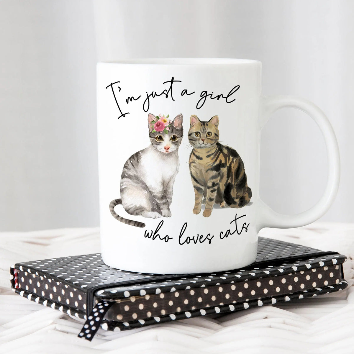 White ceramic cat mug with two cat graphics and script text, rounded handle