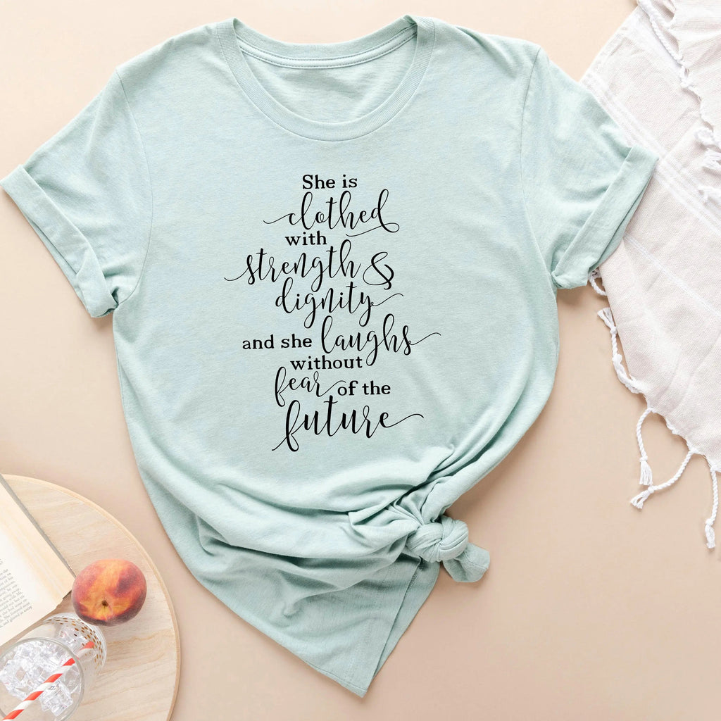 Light aqua women's graphic T-shirt with "She is clothed..." verse lettering front.