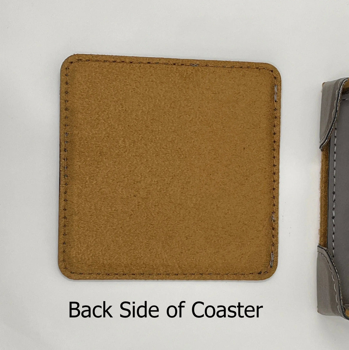 Square leather-look coaster back side in tan/brown with edge stitching and rounded corners