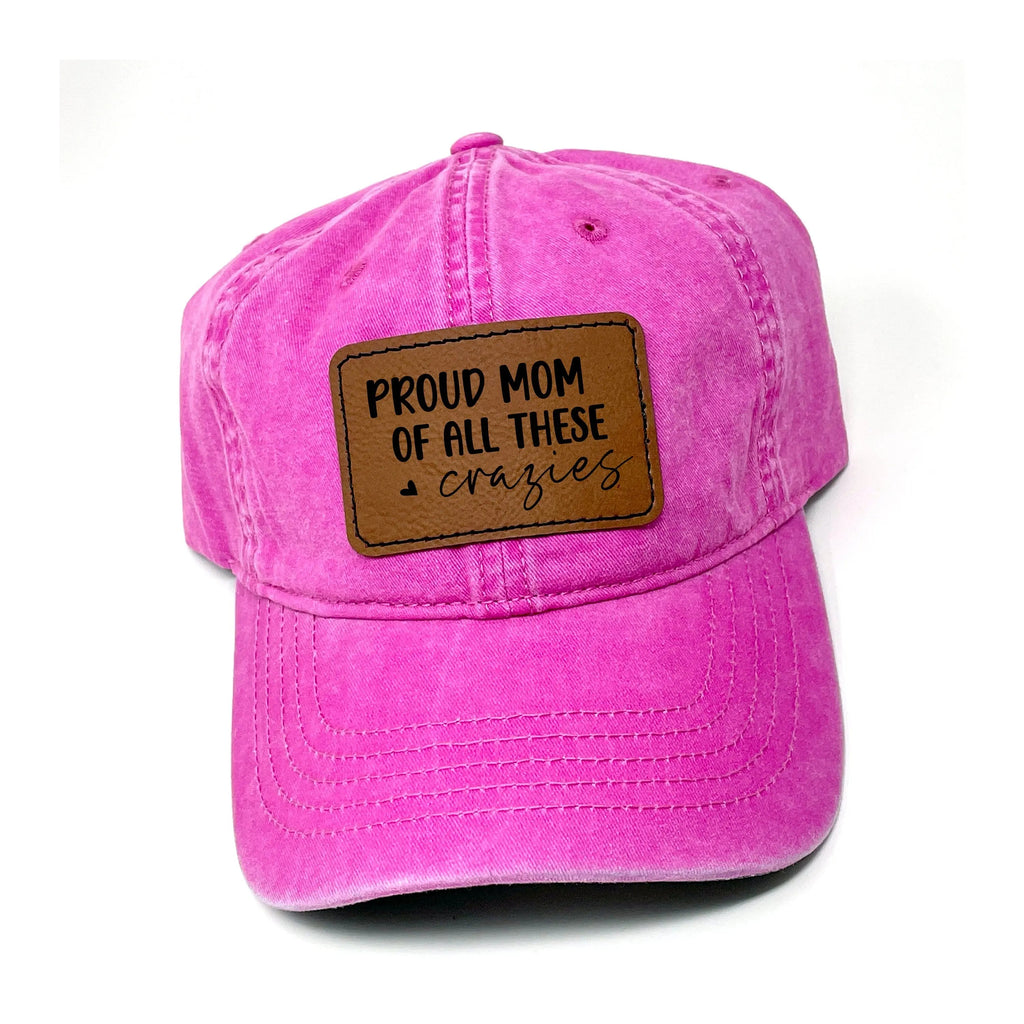Pink washed baseball cap with brown leather “Proud Mom of all these crazies” patch