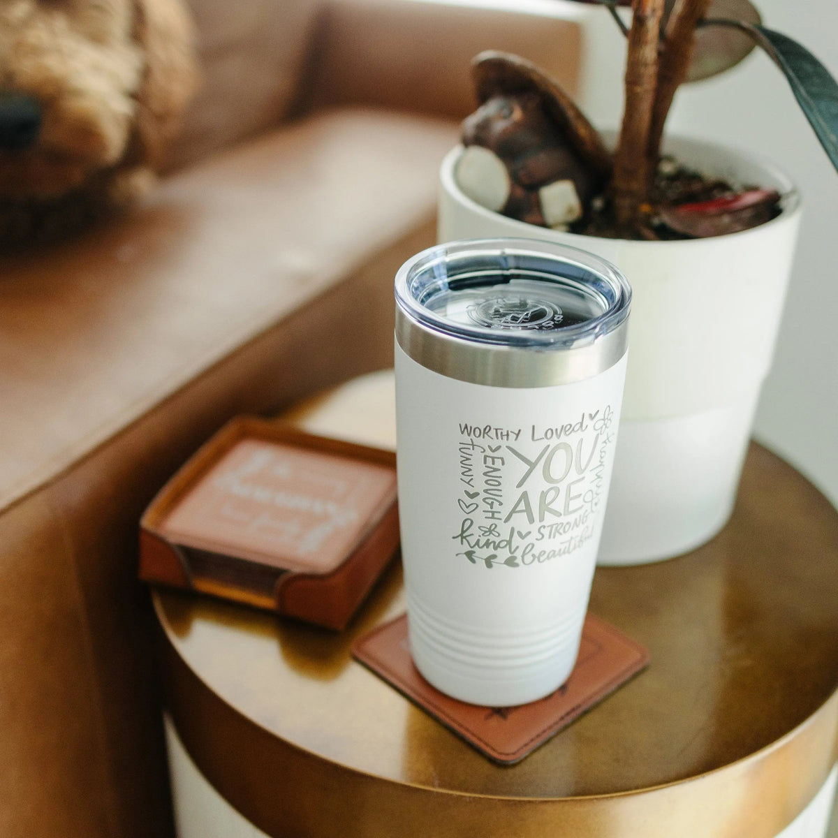 White inspirational tumbler with motivational quote on a round tray with coasters nearby.