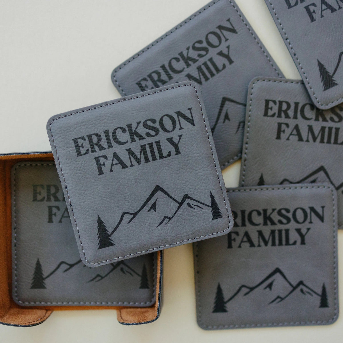 Close-up of light gray leather-look coasters with ERICKSON FAMILY text and mountain line art