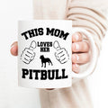 White ceramic mug with 'This Mom Loves Her Pitbull' text and black dog graphic