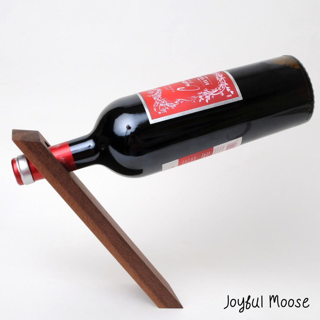 Dark wood wine bottle balancer stand holding a black bottle