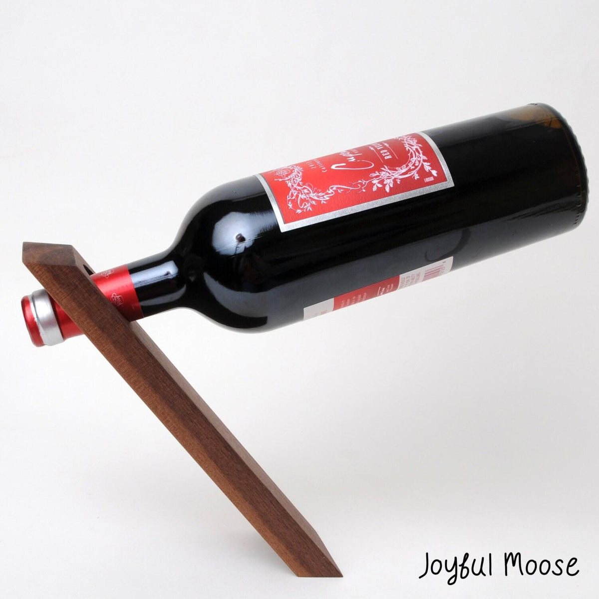 Dark wood wine bottle balancer stand holding a black bottle