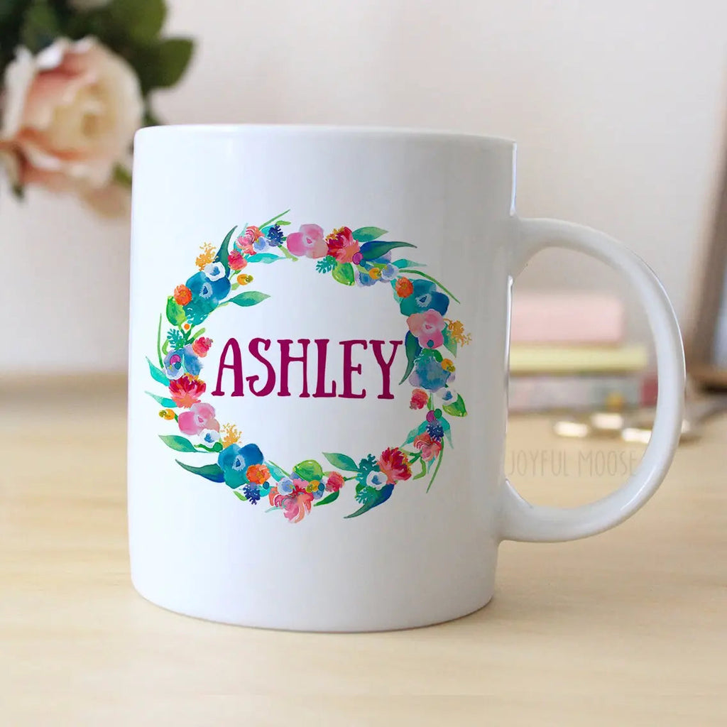 White ceramic mug with floral wreath design and "ASHLEY" printed in pink