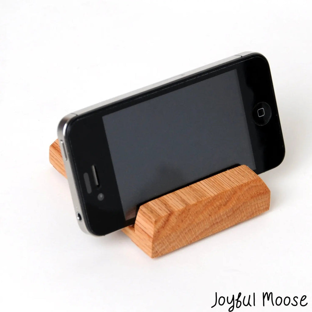Wooden iPhone stand holding a black iPhone in portrait view