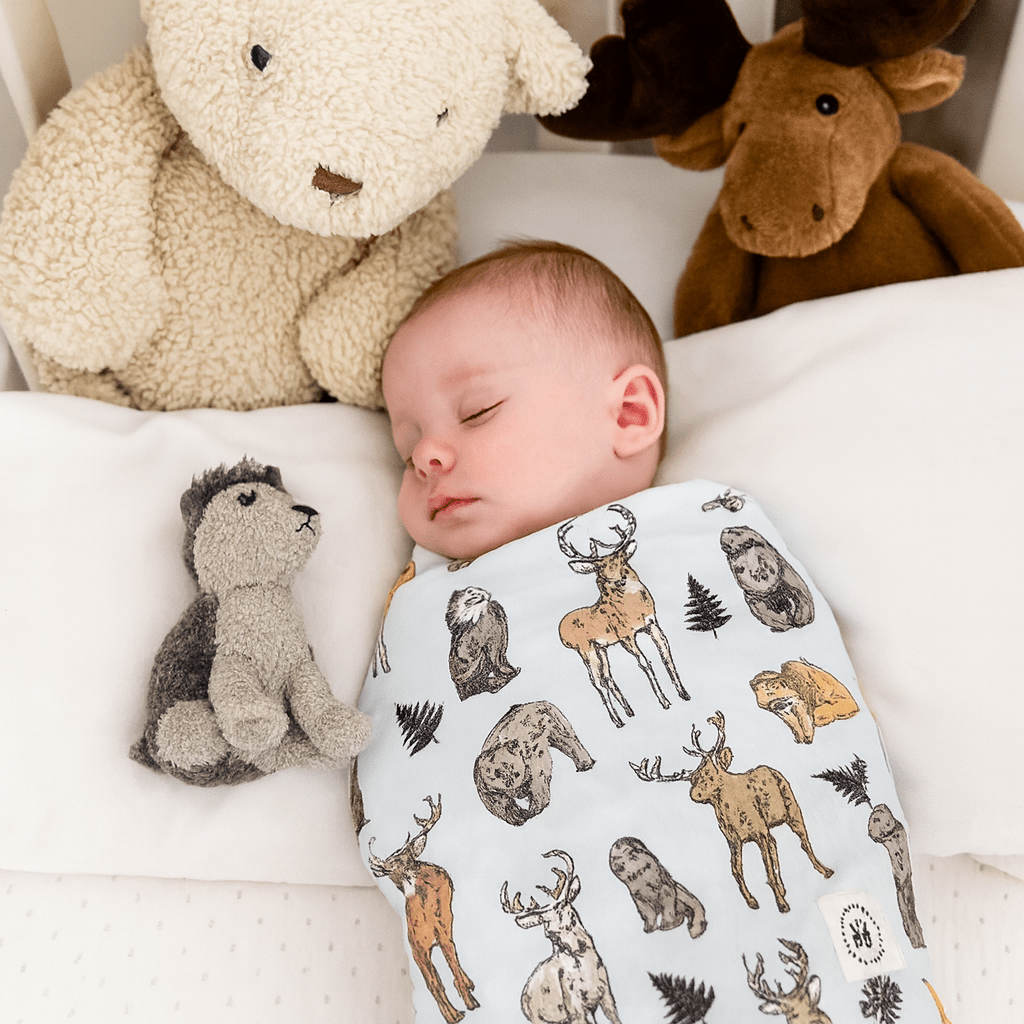 Baby swaddle blanket with cream base and woodland animal silhouettes, soft fabric