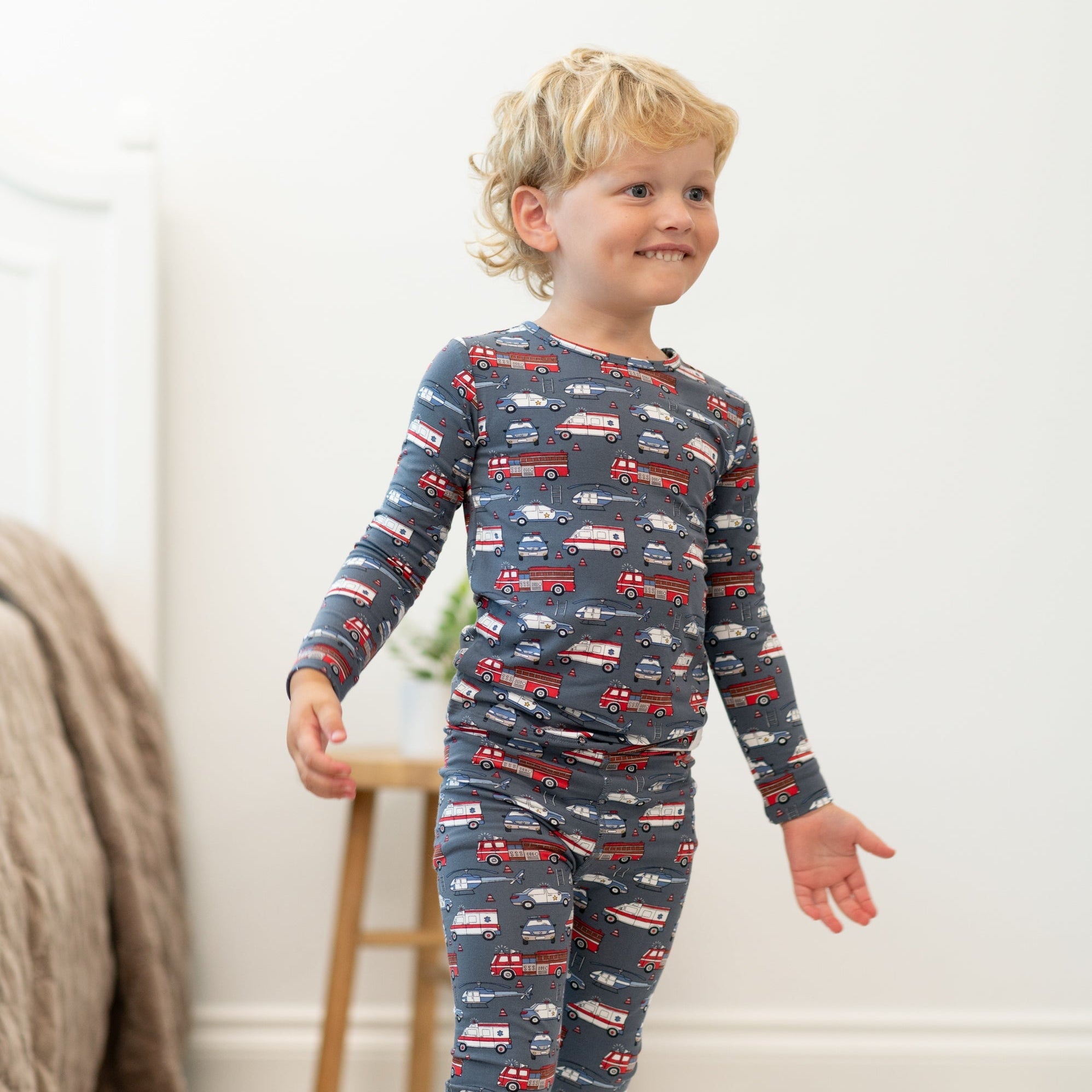 Boys long-sleeve pajamas with navy car print, smiling child standing