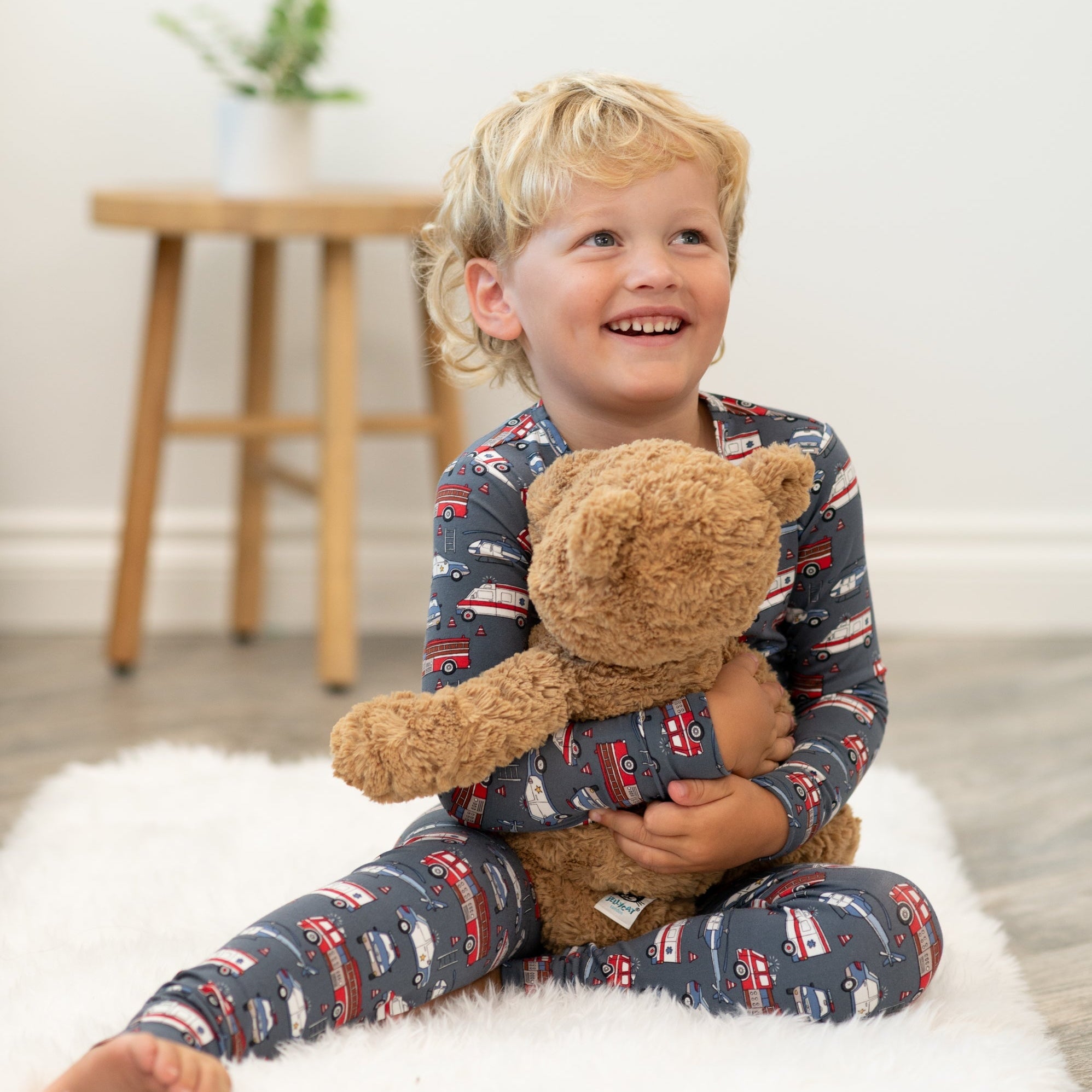 Kids pajama set, long-sleeve navy truck print, boy holding teddy bear
