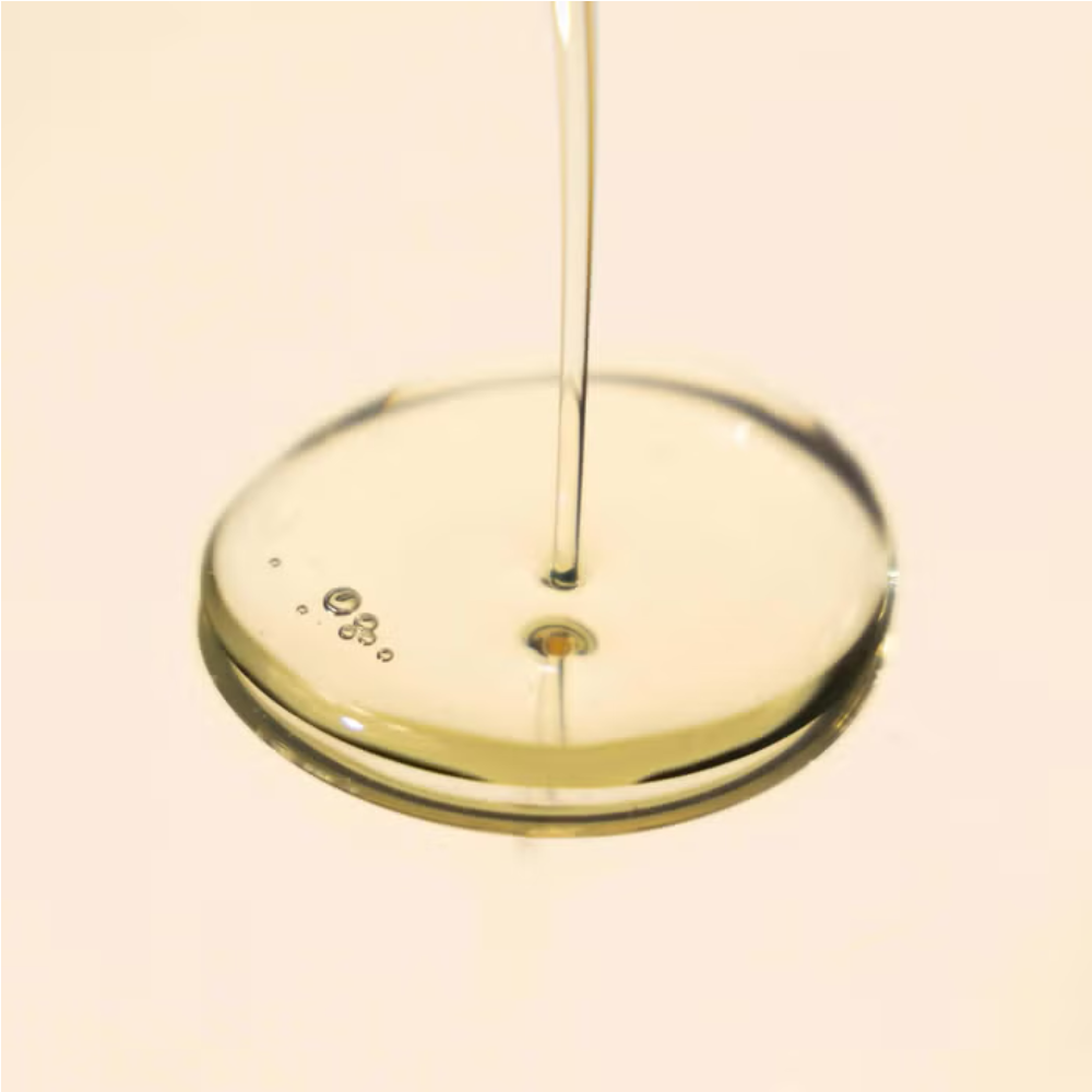 Body oil blend with clear oil being poured into a dish